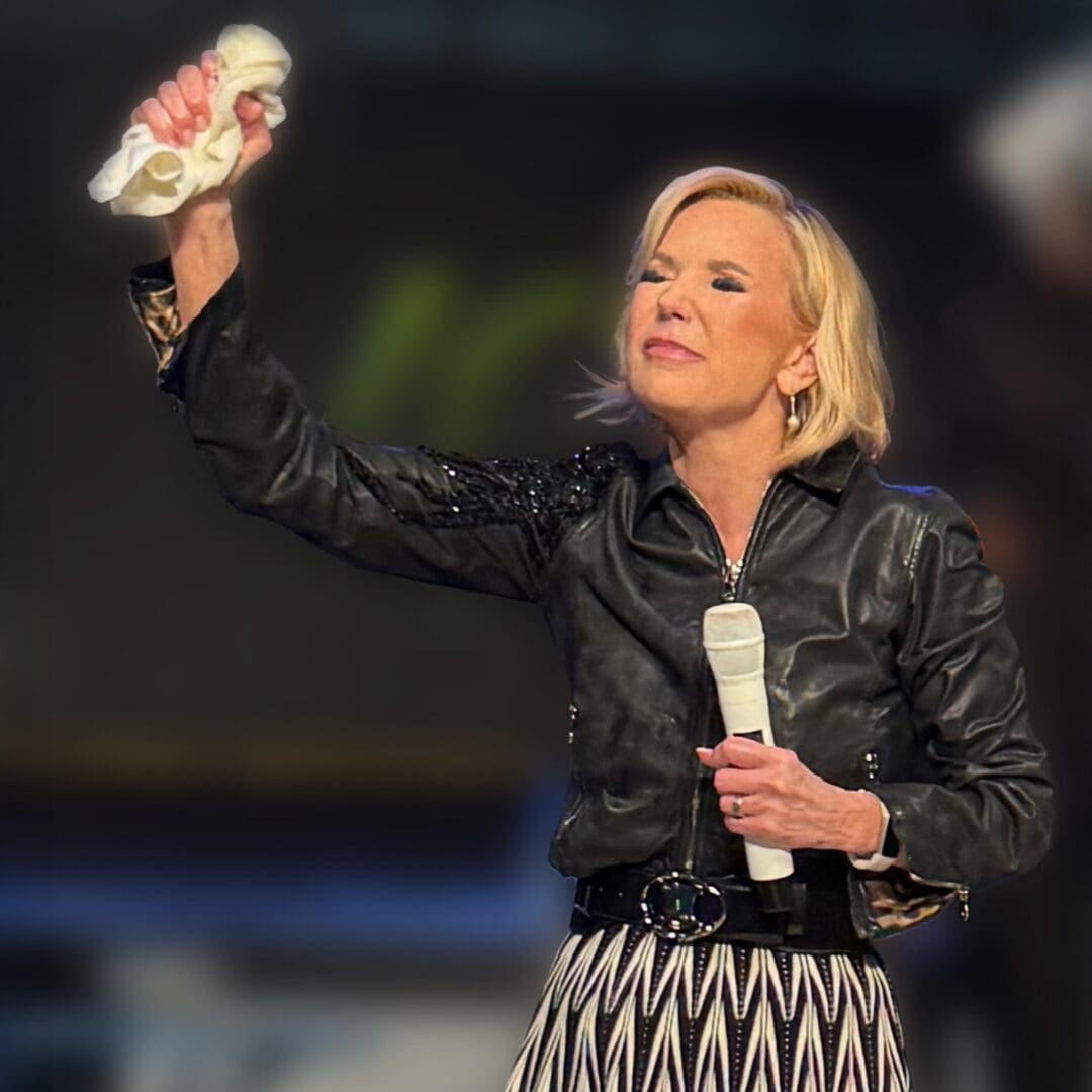 Paula White praying with microphone in hand during Paula White Ministries event